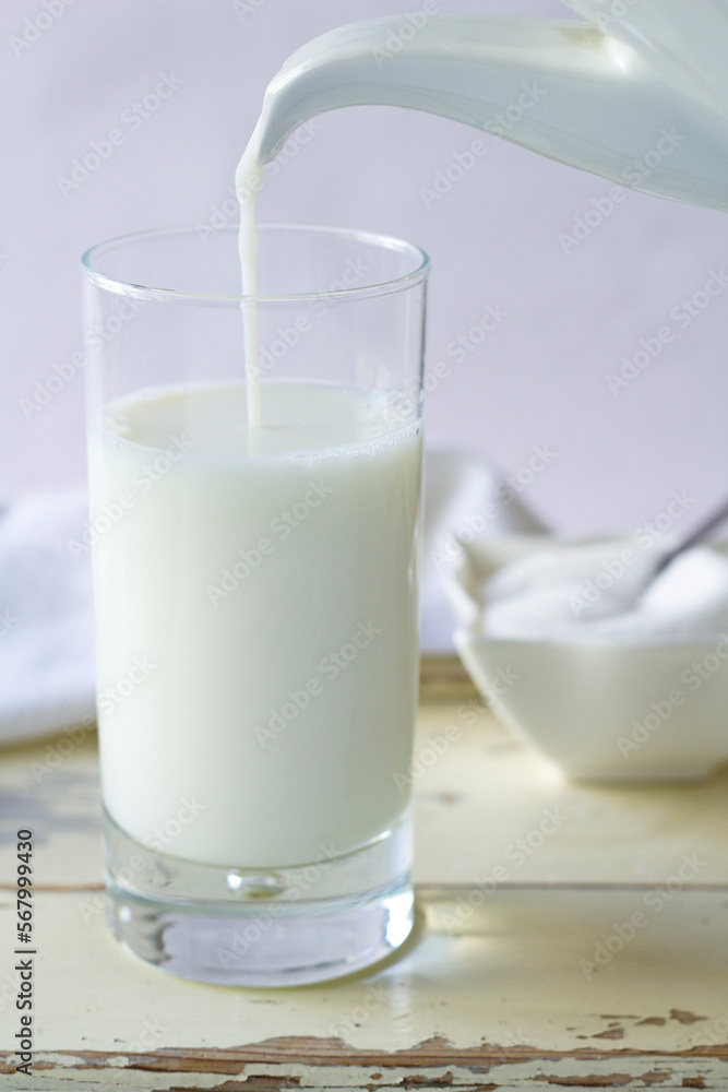 A milk jug filling a glass. A milk jug filling a glass.