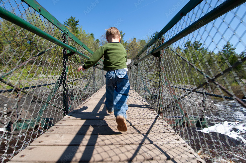 Three year old running across suspension bridge