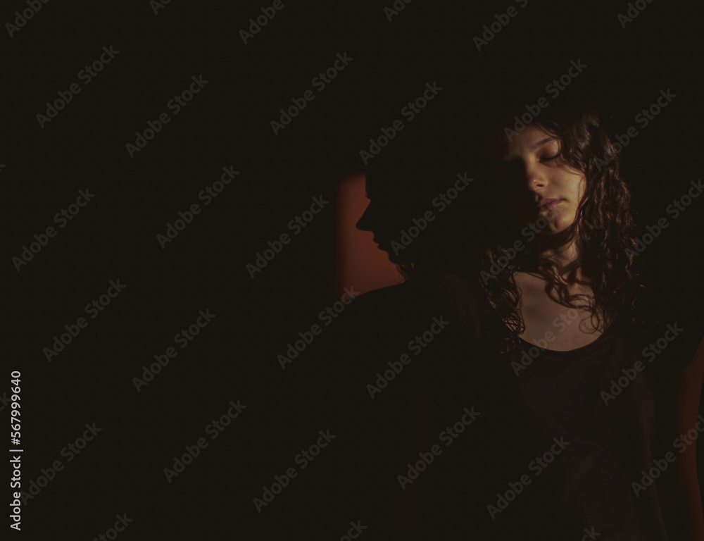 young woman on black background with light and shadow on face young woman on black background with light and shadow on face