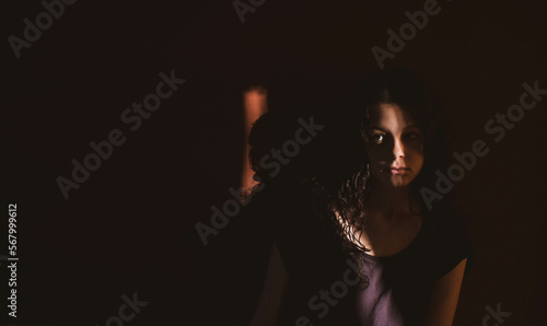 young woman on black background with light and shadow on face © Cavan
