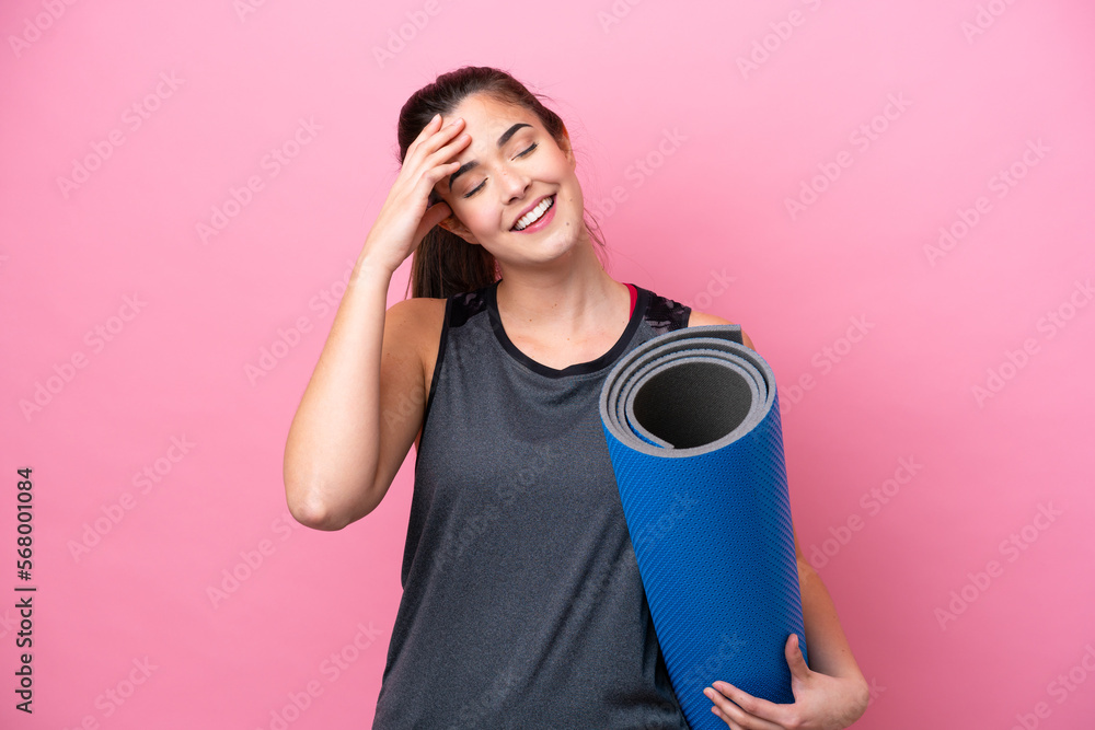 Young Brazilian sport woman going to yoga classes while holding a mat isolated on pink background smiling a lot Young Brazilian sport woman going to yoga classes while holding a mat isolated on pink background smiling a lot