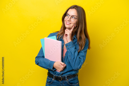 Young student caucasian woman isolated on yellow background thinking an idea while looking up