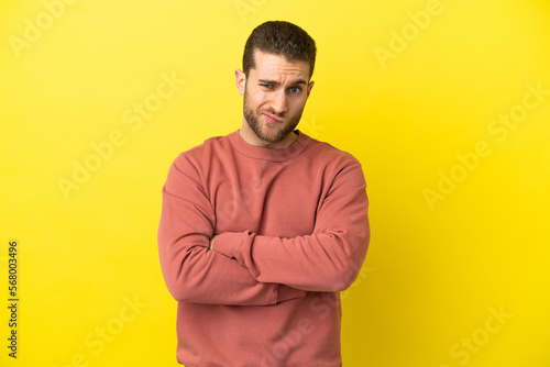 Handsome blonde man over isolated yellow background with unhappy expression