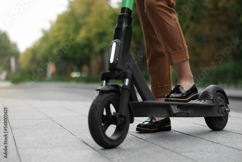 Businesswoman with modern electric kick scooter on city street, closeup. Space for text