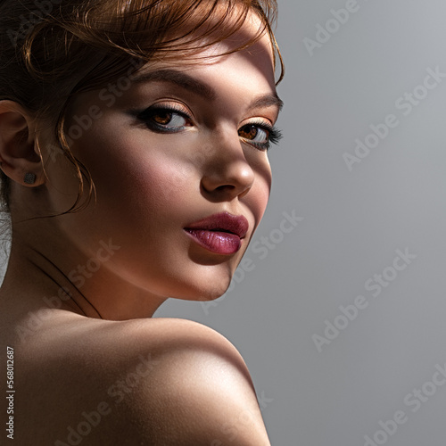 Art portrait of beautiful young woman with brown makeup. Beautiful brunette with hard shadows on her face. Model with short creative hairstyle.
