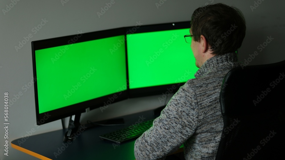 Creative Middle Aged Designer Sitting at His Desk Uses Desktop Computer with Two Green Mock-up Screens. Professional Office Employee Working Late in Evening in Studio Man taking off putting on glasses Creative Middle Aged Designer Sitting at His Desk Uses Desktop Computer with Two Green Mock-up Screens. Professional Office Employee Working Late in Evening in Studio Man taking off putting on glasses