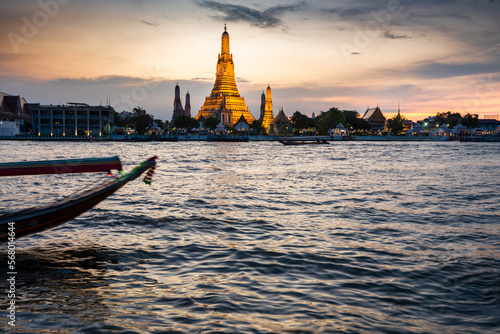Wat Arun and boat,at sunset,along the Chao Phraya river,Bangkok,Thailand.