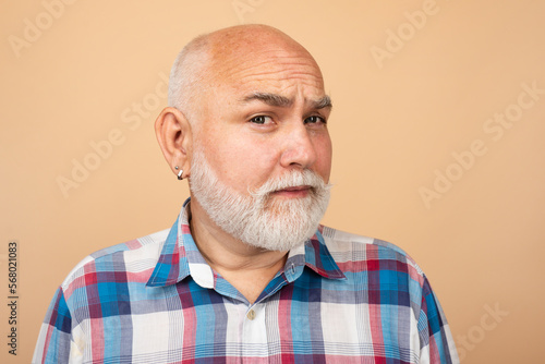 Closeup emotional portrait of an old mature senior man with grey beard isolated on studio background. Emotions faces.