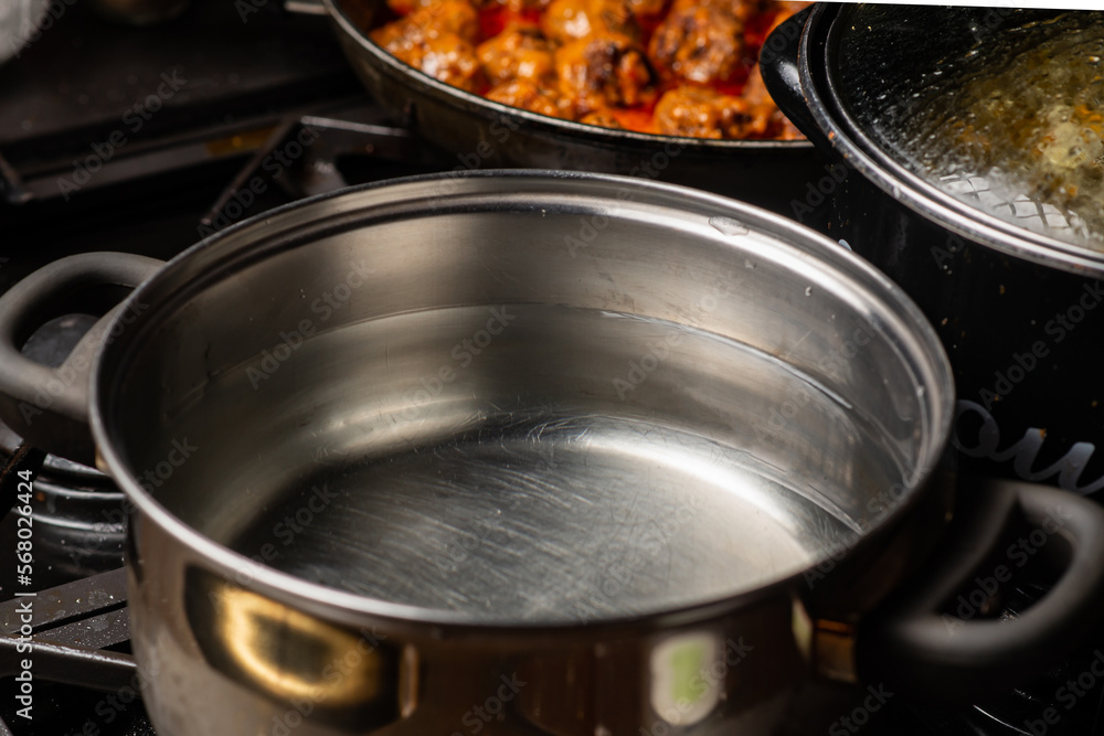 Water in a pot is on the stove in the kitchen. Preparation for boiling water. Water in a pot is on the stove in the kitchen. Preparation for boiling water.