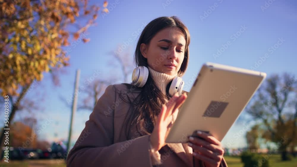 Young girl stands on embankment in city center with picturesque view of nature autumn landscape and using digital tablet. Remote work or online communication. Toothy smile and happiness. Leisure. Young girl stands on embankment in city center with picturesque view of nature autumn landscape and using digital tablet. Remote work or online communication. Toothy smile and happiness. Leisure.