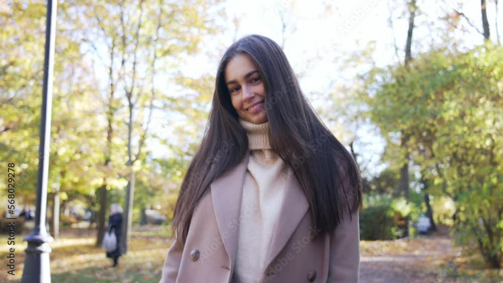 Beautiful girl walks in park and walk back, posing and looking at camera. Young woman enjoys autumn nature, happy smile. Fashionable and cozy autumn look, outfit. Rest on leisure. Active lifestyle. Beautiful girl walks in park and walk back, posing and looking at camera. Young woman enjoys autumn nature, happy smile. Fashionable and cozy autumn look, outfit. Rest on leisure. Active lifestyle.