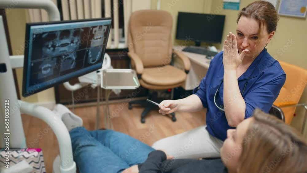 Dentist talking, gesturing and showing results of x-ray teeth on monitor screen to patient in dental chair. Cabinet in tooth clinic. Preventive examination. Treatment, healthcare and medicine. Dentist talking, gesturing and showing results of x-ray teeth on monitor screen to patient in dental chair. Cabinet in tooth clinic. Preventive examination. Treatment, healthcare and medicine.