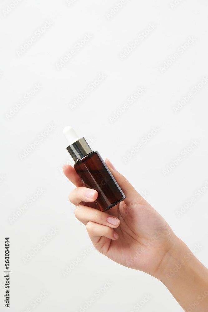 갈색 화장품 공병을 들고 있는 여성의 손 갈색 화장품 공병을 들고 있는 여성의 손