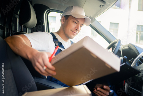 The driver is a male courier company in the car. A courier employee delivering boxes by car to the customer's order address.