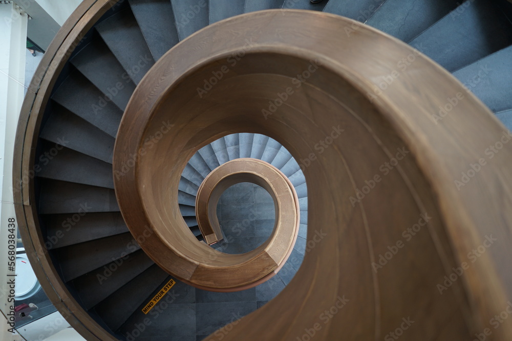 Fototapeta premium Top down view of the spiral staircase with wooden handle