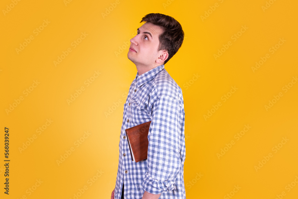 A handsome guy with a book on a yellow background A handsome guy with a book on a yellow background