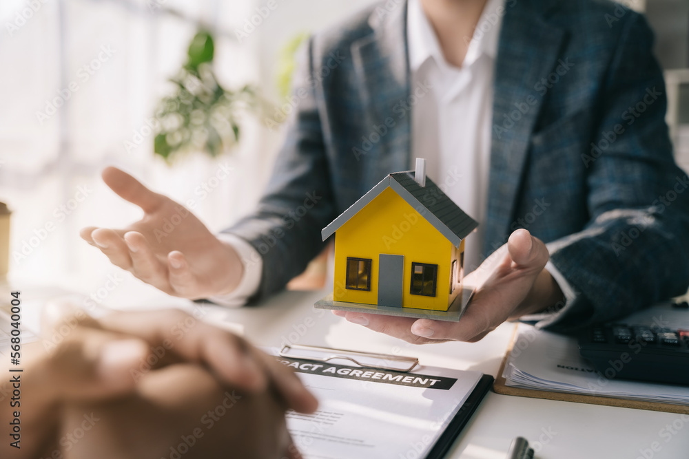 Real estate broker agent presenting and consult to customer to decision making sign insurance form agreement, home model, concerning mortgage loan offer in office.