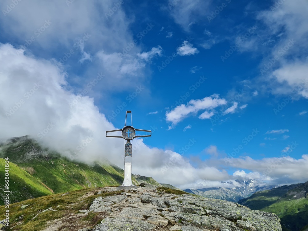 A metal summit cross of the top of Bockhartscharte in Austrian Alps. Hohe Tauern. Clear and sunny day. Outdoor activity. Barren top of the mountains A metal summit cross of the top of Bockhartscharte in Austrian Alps. Hohe Tauern. Clear and sunny day. Outdoor activity. Barren top of the mountains
