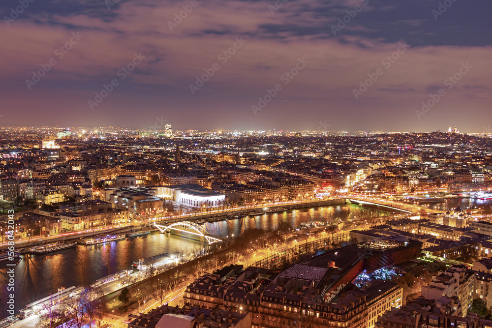 A breathtaking panoramic view from the Eiffel Tower of evening Paris in the bright lights of illumination