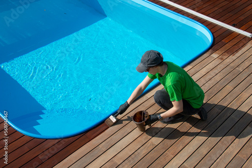 Seasonal restoration of wooden deck around the swimming pool, decking oil application