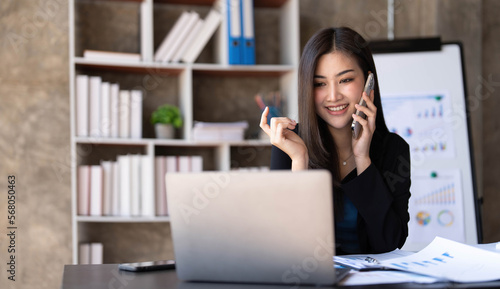 Portrait of young asian business woman talk on smartphone write notebook laptop in home office. Beautiful girl at desk computer take home order. Startup business asia woman online sme telemarketing.