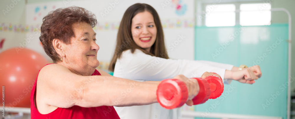 Old senior woman exercising on physical therapy with help of the physical therapist in the hospital Old senior woman exercising on physical therapy with help of the physical therapist in the hospital