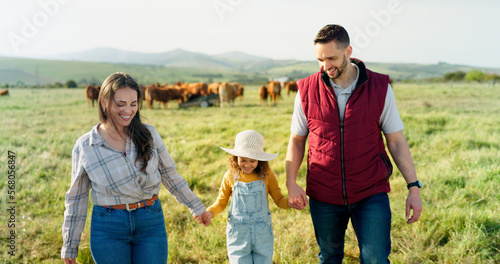 Farm, family and cattle with a girl, mother and father walking on a field for agriculture or sustainability farming. Farmer, love and parents with a daughter on a grass meadow with cows on a ranch