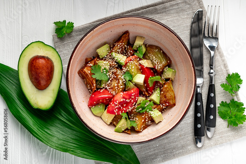 Fried eggplant with avocado, tomatoes and sesame seeds. Asian cuisine.