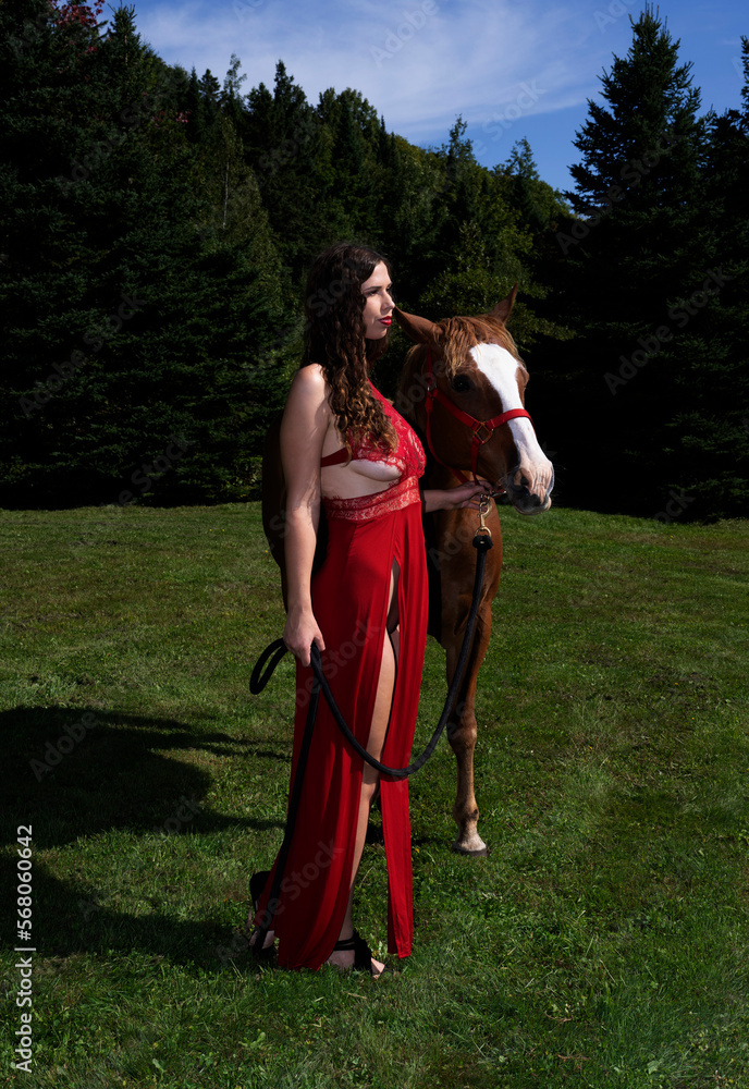 A woman in a long red dress with her horse