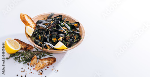 Fresh mussels in a wooden plate with herbs and lemon