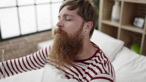 Young redhead man somnambulist sitting on bed at bedroom