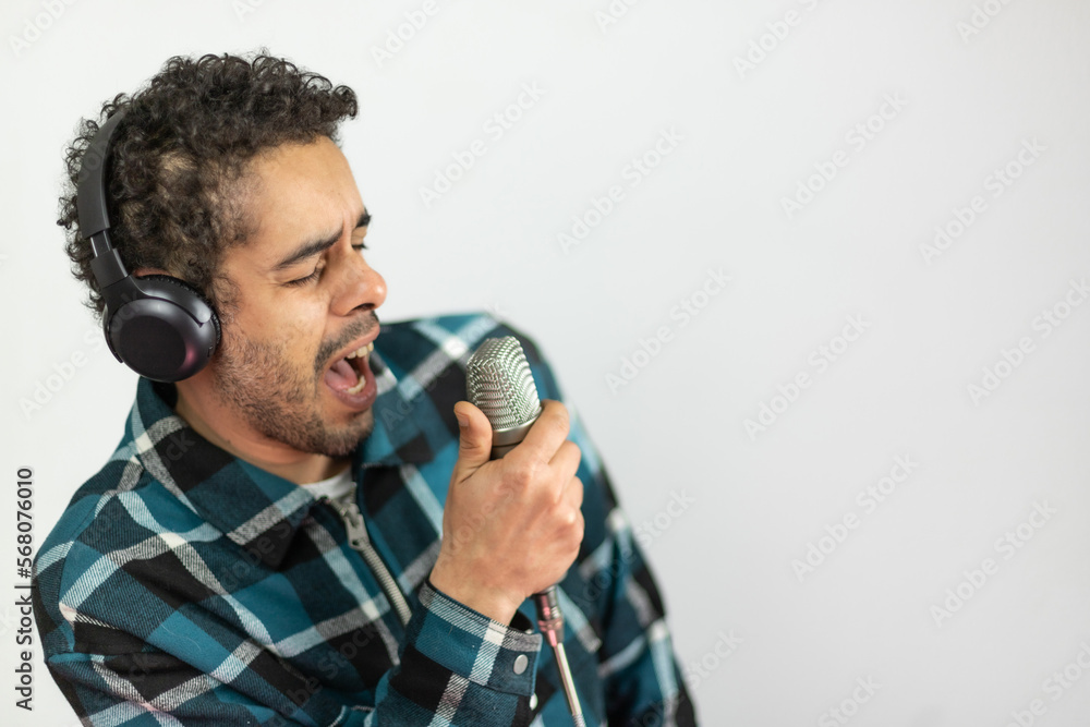 Naklejka premium Mixed race man dressed in checked shirt singing into a condenser microphone