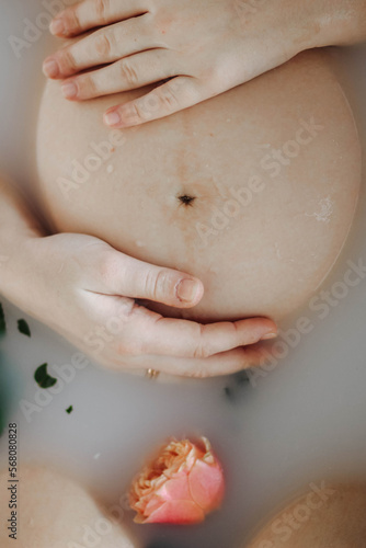 Cropped view of pregnant woman taking bath with flowers and milk