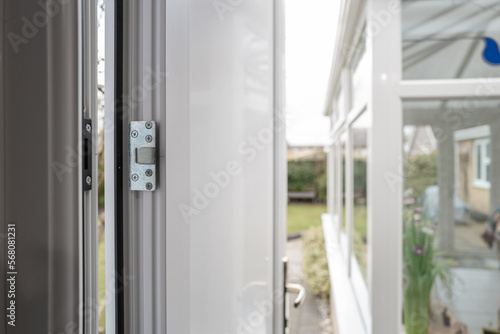 Shallow focus of a new  high security side door installed into a garage. The back garden and conservatory are seen.