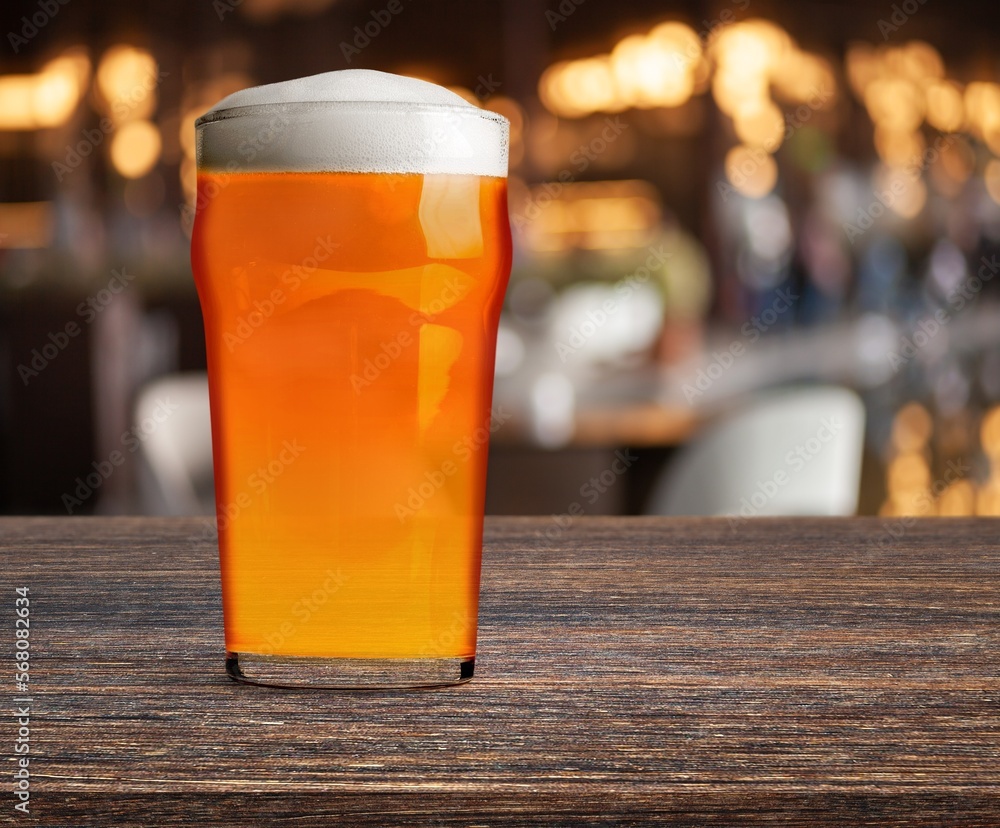 Pint glass of beer in bar on the desk Pint glass of beer in bar on the desk
