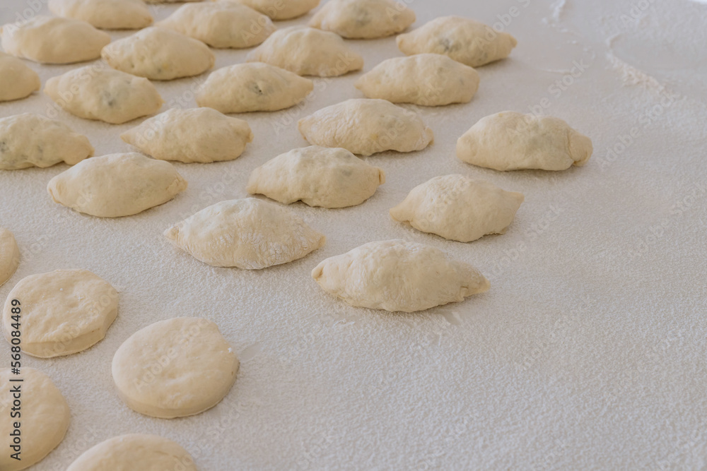 Preparation for baking buns with stuffing and donuts on white countertop using of yeast dough
