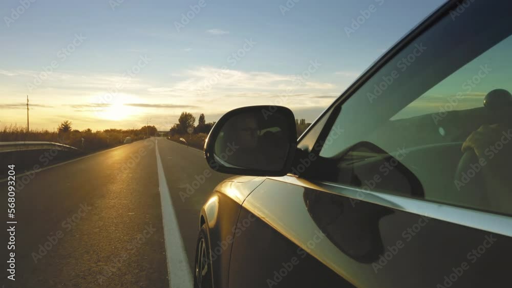 Driver view in the rear view of the sports car speeding on the road at sunset