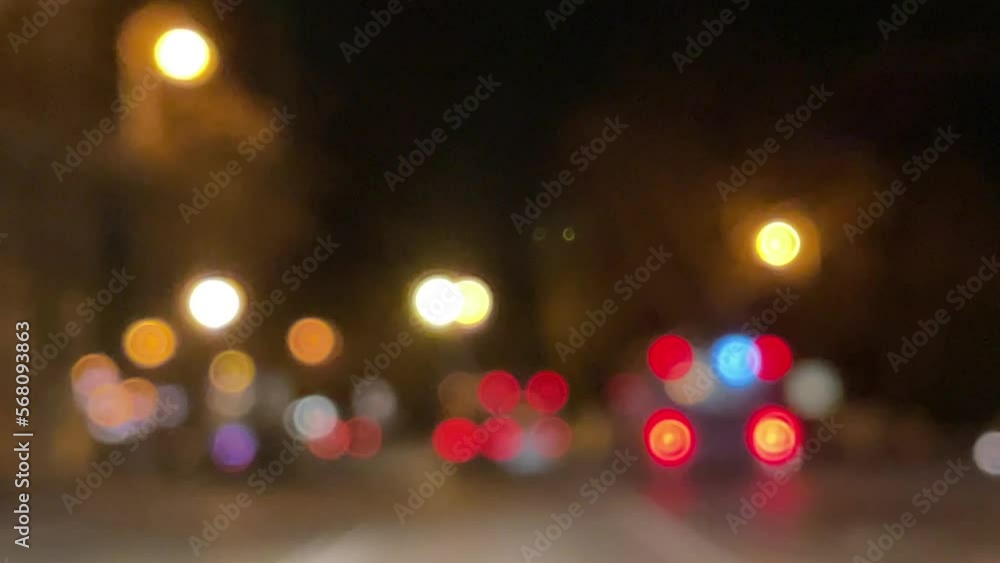 Blurred car lights bokeh in the evening city. Defocused headlights and street lighting at night. Moving bokeh circles of cars at night. Blurred city traffic background Blurred car lights bokeh in the evening city. Defocused headlights and street lighting at night. Moving bokeh circles of cars at night. Blurred city traffic background