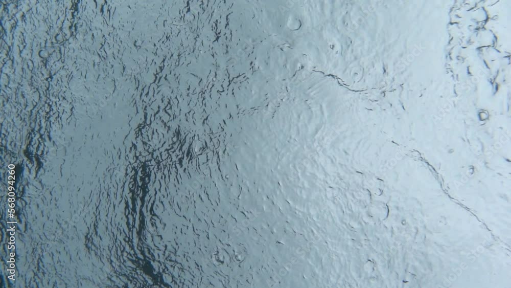 Rain drops falling on the water surface. Underwater view, slow motion Rain drops falling on the water surface. Underwater view, slow motion