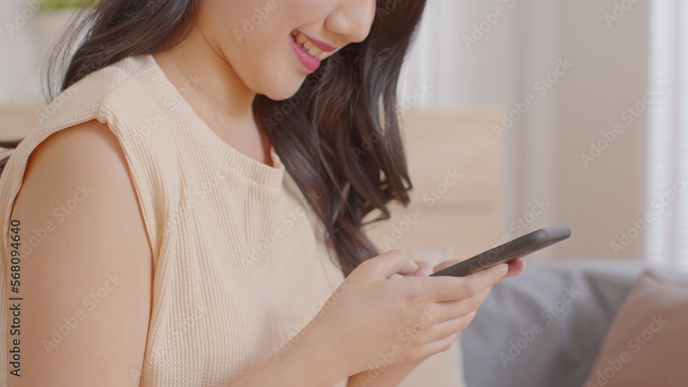 Happy asian young woman smile using smartphone surfing internet and enjoy with social media or online shopping at home. Modern wellness life of cute female looking at mobile phone fun and happiness Happy asian young woman smile using smartphone surfing internet and enjoy with social media or online shopping at home. Modern wellness life of cute female looking at mobile phone fun and happiness