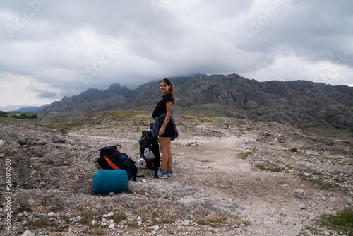 Panoramic view of a woman hiking along the trail across the rock massif The Giants in Cordoba, Argentina. View of the female hiker with her gear and rocky hills in the background in a cloudy morning. 