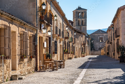 Street of beautiful medieval buildings with church tower in the background in the monumental city of Pedraza, Segovia, Spain. photo