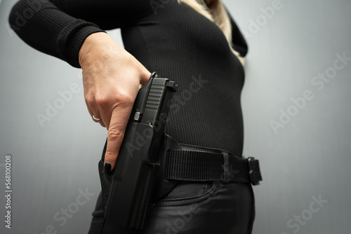 The girl pulls out a gun from the holster, close-up photo.