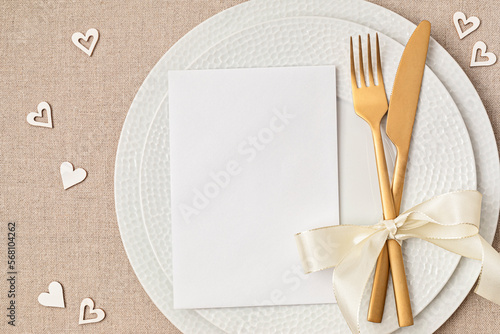 Festive wedding, birthday table setting with golden cutlery and porcelain plate. Blank card mockup. Party menu template. Flat lay, top view