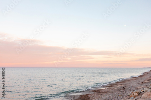 Pastel sunset on beach with tiny crescent moon