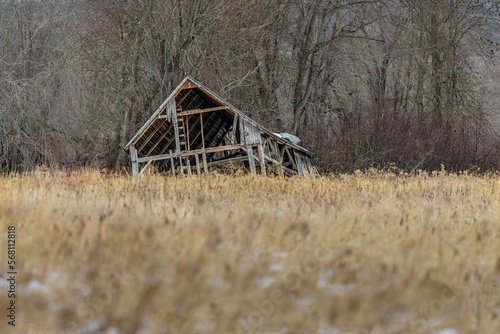 Abandoned derelict shack falling apart at edge of brown field