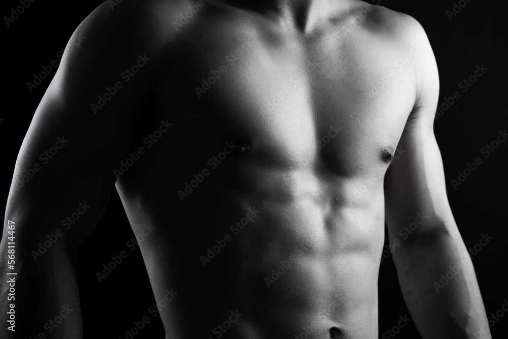 Close up view of sexy body of young man with six pack muscular and athletic body on black background. concept of health care, exercise, fitness, muscle mass, health supplements.