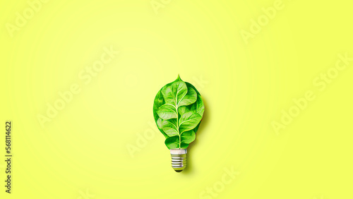 Green energy concept. Energy saving technology, light bulb with green leaves on yellow background