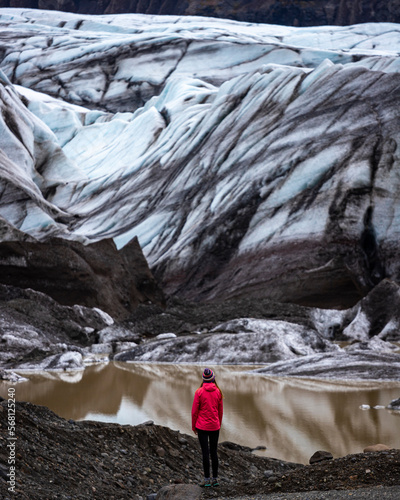 woman standing in front large blue glacier of svínafellsjökull in iceland; huge blue glacier in front of little girl