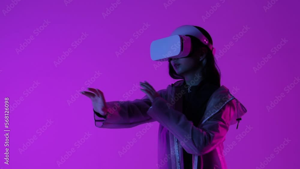 Woman in futuristic costume. Female in modern VR glasses interacting with network while having virtual reality experience. Augmented reality game, future technology, AI concept. VR. Neon light. Woman in futuristic costume. Female in modern VR glasses interacting with network while having virtual reality experience. Augmented reality game, future technology, AI concept. VR. Neon light.
